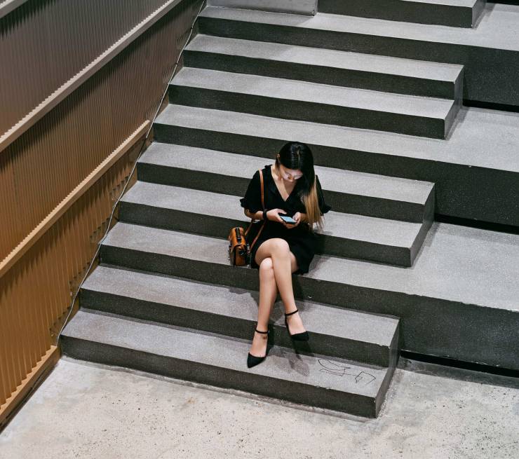 Woman in black dress on concrete stairs.