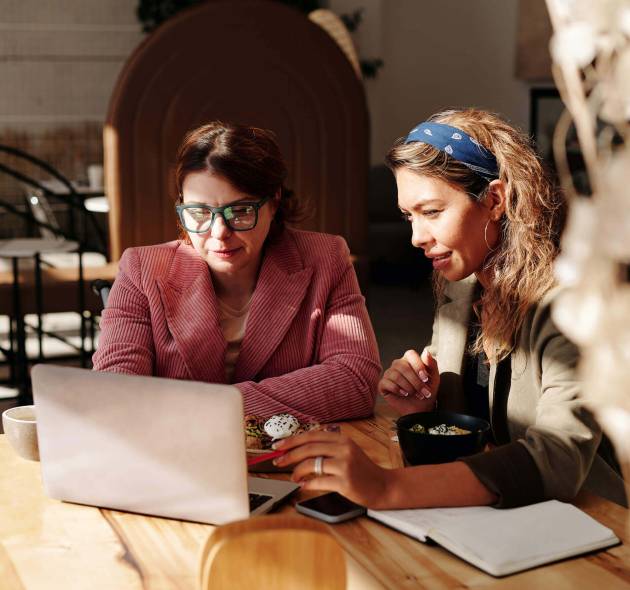 Two women working on a laptop at a cafe.